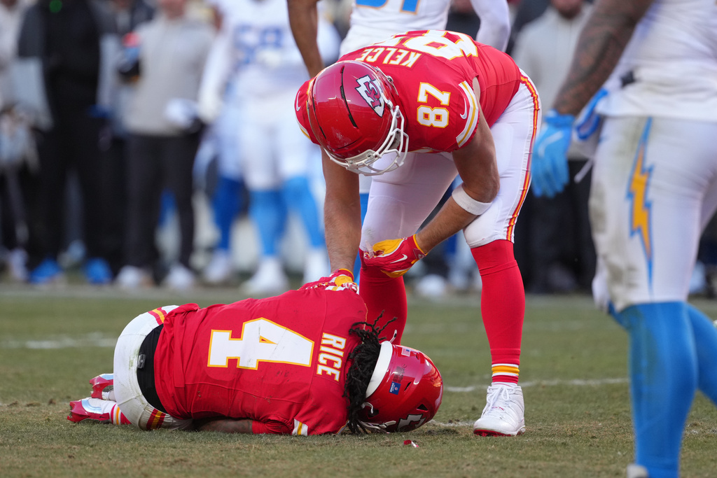 Kansas City Chiefs wide receiver Rashee Rice (4) is checked on by teammate Travis Kelce (87) after being injured during the second half of an NFL football game against the Los Angeles Chargers Sunday, Dec. 14, 2025, in Kansas City, Mo. (AP Photo/Ed Zurga)