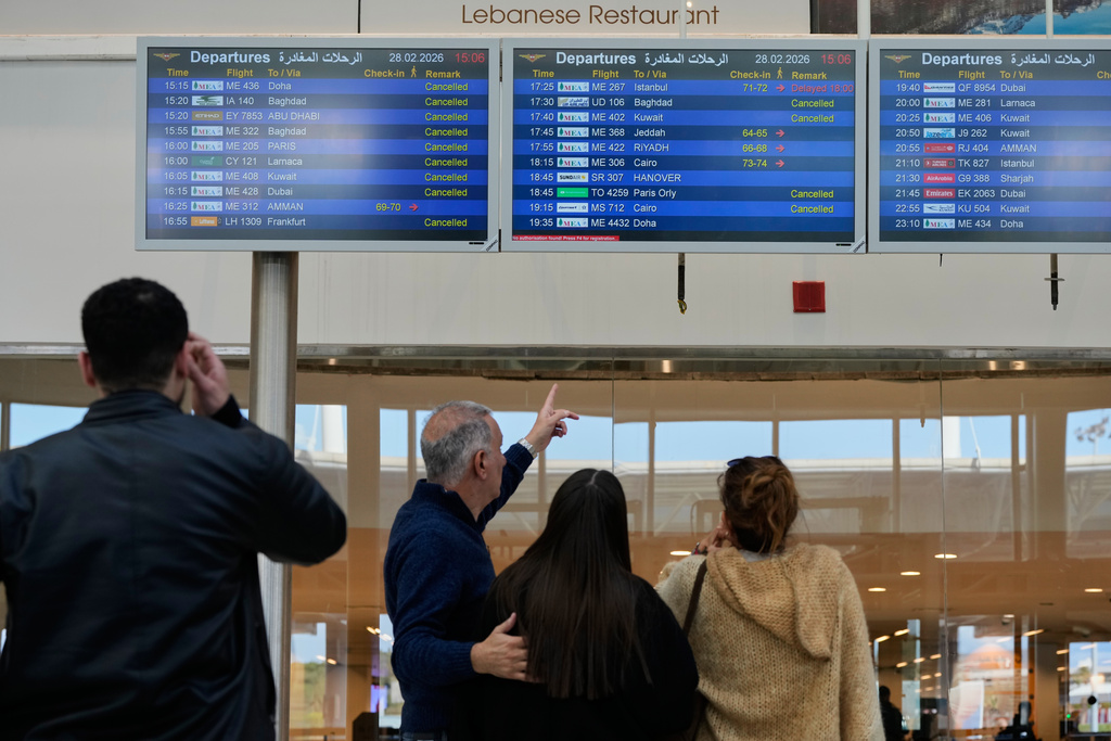 Travelers check departure times as many flights are cancelled at Beirut Rafik Hariri International Airport in Beirut, Lebanon, Saturday, Feb. 28, 2026, as many airlines canceled flights due to the conflict involving the United States, Israel and Iran. (AP Photo/Hassan Ammar)