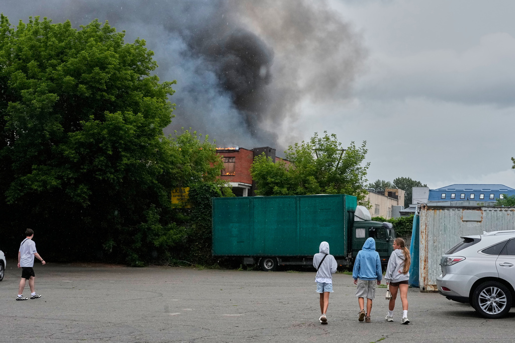 People look at a burning private enterprise following Russian drone attack in Kyiv, Ukraine, Wednesday, July 8, 2026. (AP Photo/Efrem Lukatsky)