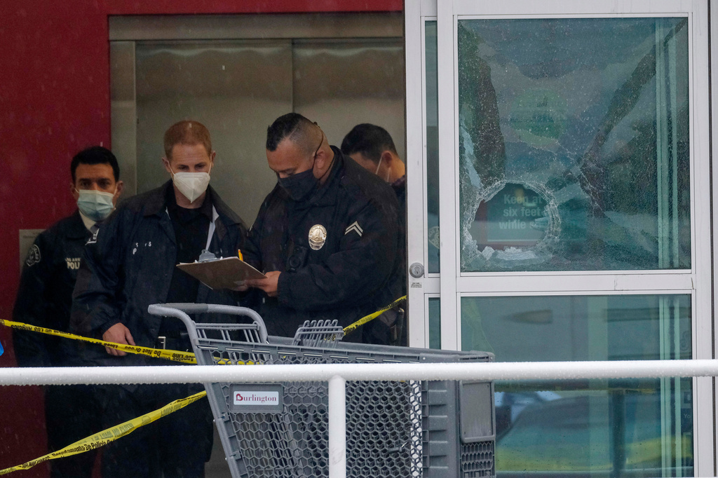 FILE - Police officers work near a broken glass door at the scene where two people were struck by gunfire in a shooting at a Burlington store, Dec. 23, 2021, in North Hollywood, Calif. (AP Photo/Ringo H.W. Chiu, File)