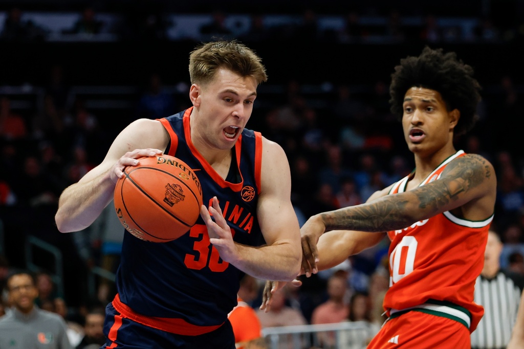 Virginia guard Dallin Hall, left, drives against Miami guard Tru Washington during the first half of an NCAA college basketball game in the semifinals of the Atlantic Coast Conference tournament in Charlotte, N.C., Friday, March 13, 2026. (AP Photo/Nell Redmond)