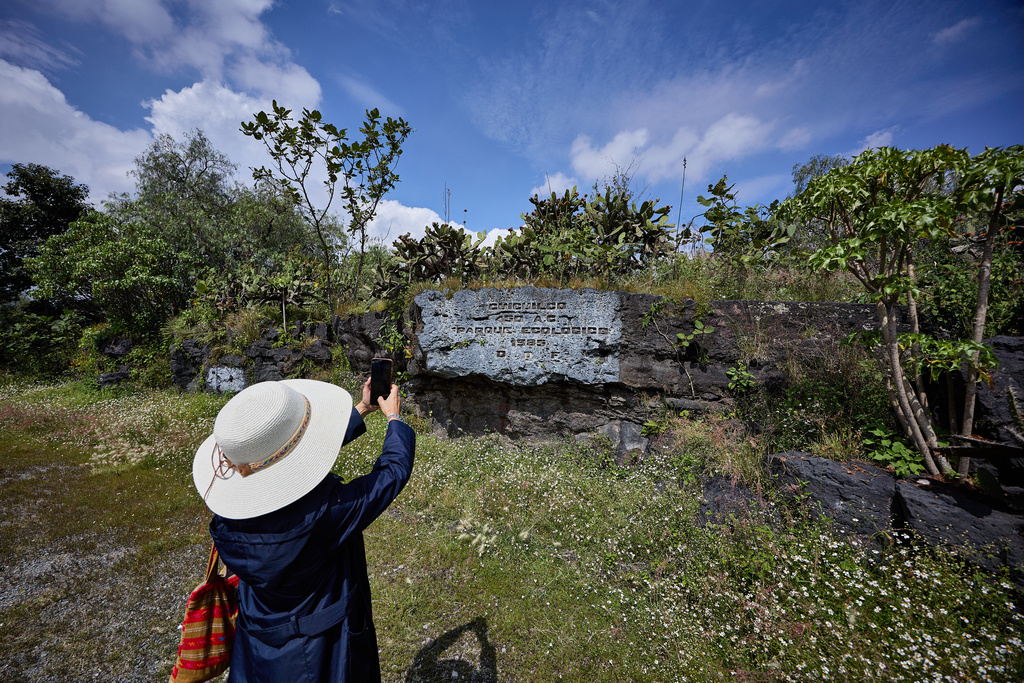 A tourist takes a photograph of the stone plaque at the Cuicuilco Archaeological Zone during a tour organized by the National Institute of Anthropology and History in Mexico City, Sunday, Oct. 5, 2025. (AP Photo/Ginnette Riquelme)
