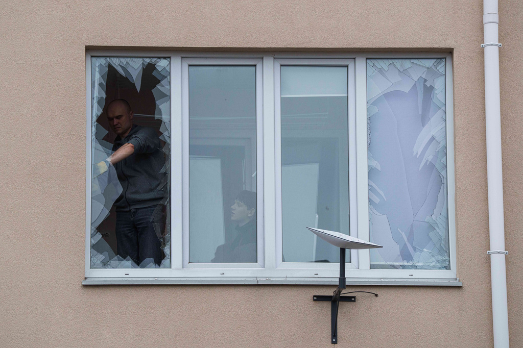 People remove broken glass from their windows after a Russian strike on residential neighbourhood in Kriukivshchyna, Kyiv region, Ukraine, on Friday, April 3, 2026. (AP Photo/Evgeniy Maloletka)