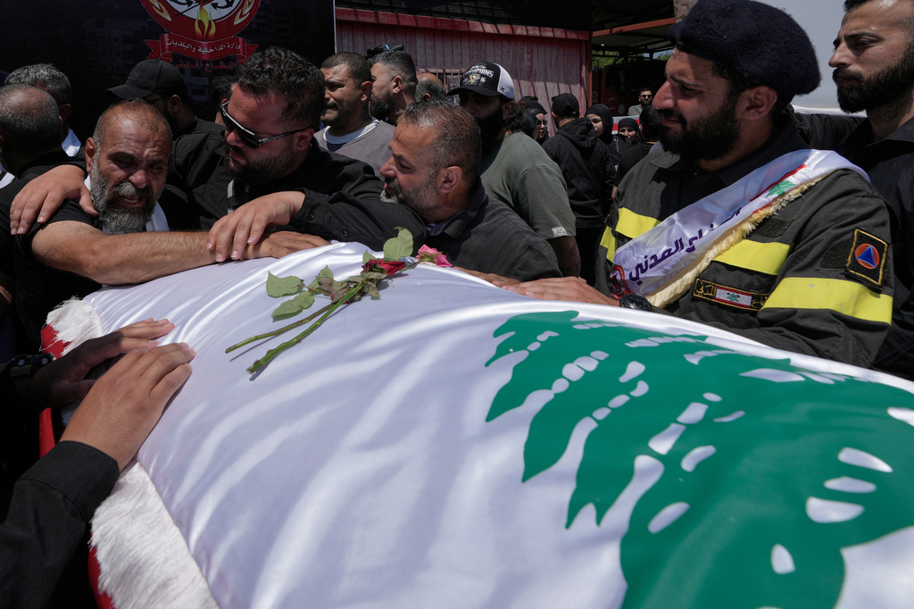 Mourners grieve over the coffin of one of three Lebanese Civil Defense workers killed in an Israeli strike on Tuesday during their funeral procession in the southern port city of Tyre, Lebanon, Thursday, April 30, 2026. (AP Photo/Hussein Malla)