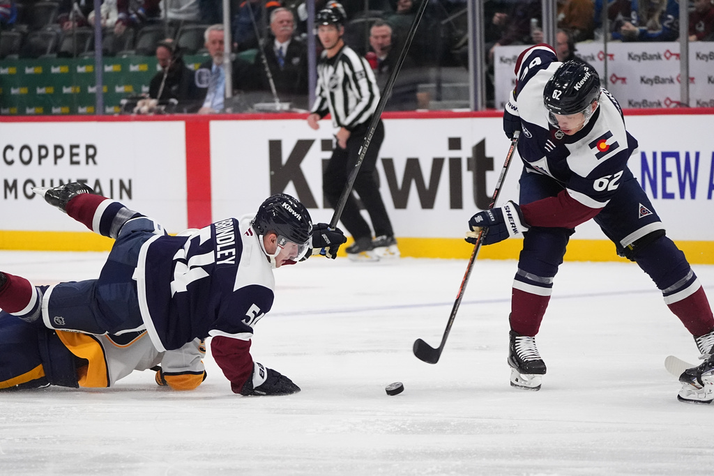 Colorado Avalanche left wing Artturi Lehkonen, right, collects the puck as Colorado Avalanche center Gavin Brindley, top left, falls on Nashville Predators defenseman Roman Josi in the first period of an NHL hockey game, Saturday, Dec. 13, 2025, in Denver. (AP Photo/David Zalubowski)