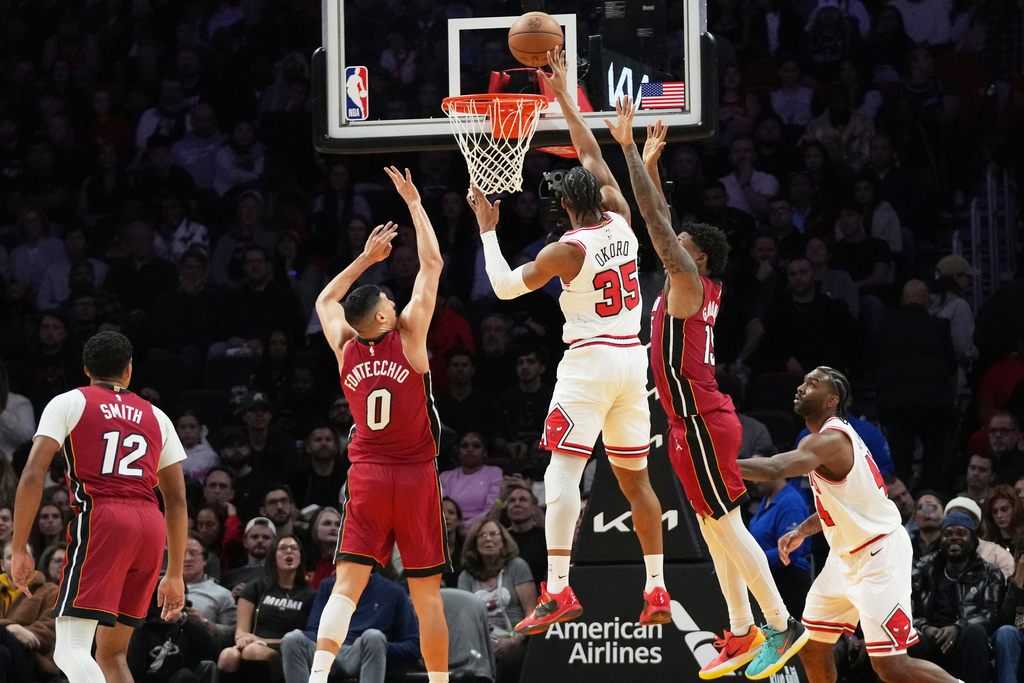 Chicago Bulls forward Isaac Okoro (35) shoots as Miami Heat forward Simone Fontecchio (0) and forward Myron Gardner, second from right, defend during the first half of an NBA basketball game, Saturday, Jan. 31, 2026, in Miami. (AP Photo/Lynne Sladky)