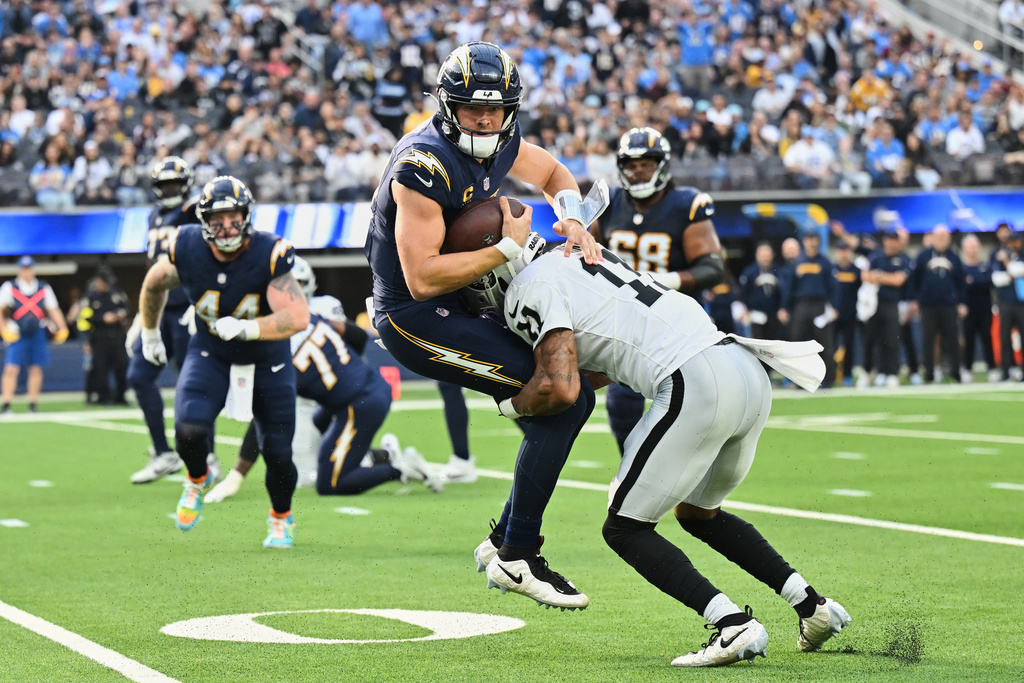 Los Angeles Chargers quarterback Justin Herbert (10) is tackled by Las Vegas Raiders safety Jeremy Chinn (11) during the first half of an NFL football game, Sunday, Nov. 30, 2025, in Inglewood, Calif. (AP Photo/William Liang)