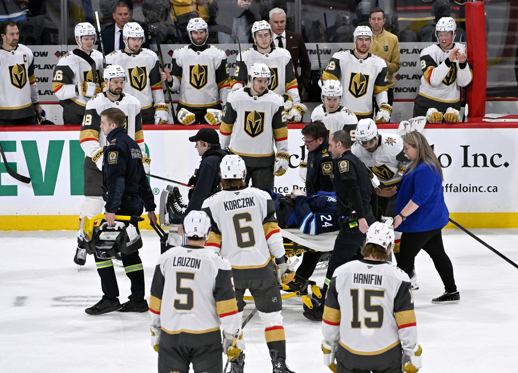Winnipeg Jets' Haydn Fleury (24) is helped off the ice after being injured during the first period of an NHL hockey game against the Vegas Golden Knights in Winnipeg, Manitoba, Tuesday Jan. 6, 2026. (Fred Greenslade/The Canadian Press via AP)
