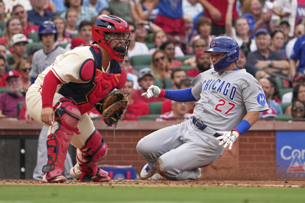 Chicago Cubs' Seiya Suzuki (27) scores past St. Louis Cardinals catcher Yohel Pozo during the second inning of a baseball game Saturday, Aug. 9, 2025, in St. Louis. (AP Photo/Jeff Roberson)