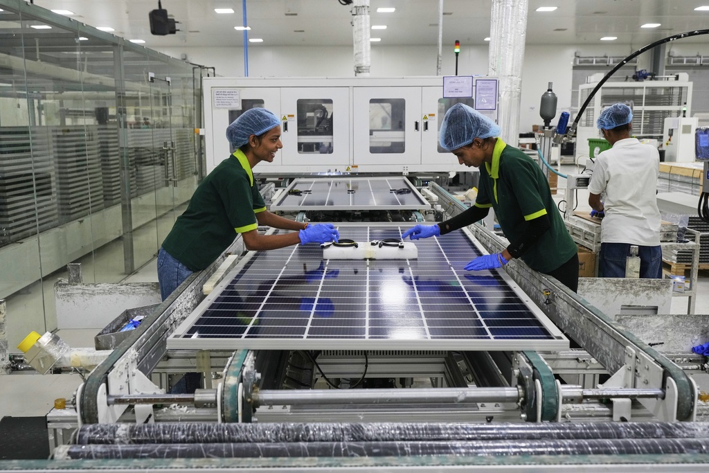 Workers put switches and connectors after they come out of automated framing at a ReNew solar panel manufacturing plant on the outskirts of Jaipur, India, Thursday, Aug. 21, 2025. (AP Photo/Manish Swarup)