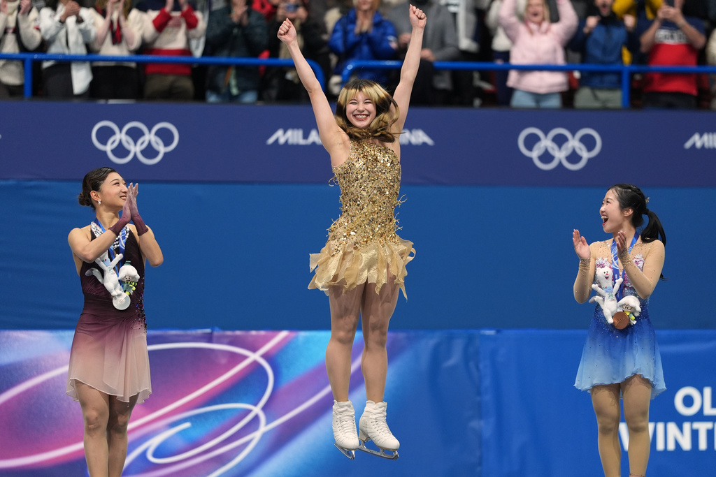 From left to right, silver medalist Kaori Sakamoto of Japan, gold medalist Alysa Liu of the United States, and bronze medalist Ami Nakai of Japan, jump on the podium to receive their medals after competing in the women's free skate program in figure skating at the 2026 Winter Olympics, in Milan, Italy, Thursday, Feb. 19, 2026. (AP Photo/Stephanie Scarbrough)