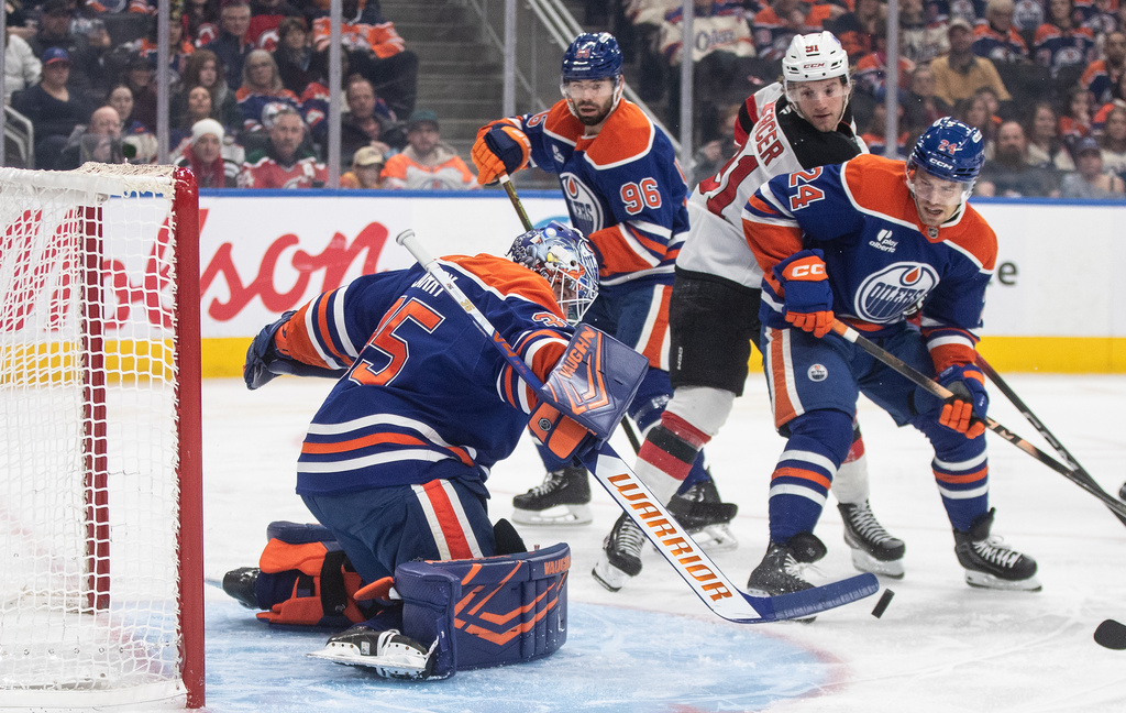 New Jersey Devils' Dawson Mercer (91) and Edmonton Oilers' Spencer Stastney (24) battle in front as goalie Tristan Jarry (35) makes the save during first period NHL action in Edmonton, Alberta, Tuesday, Jan. 20, 2026. (Jason Franson/The Canadian Press via AP)