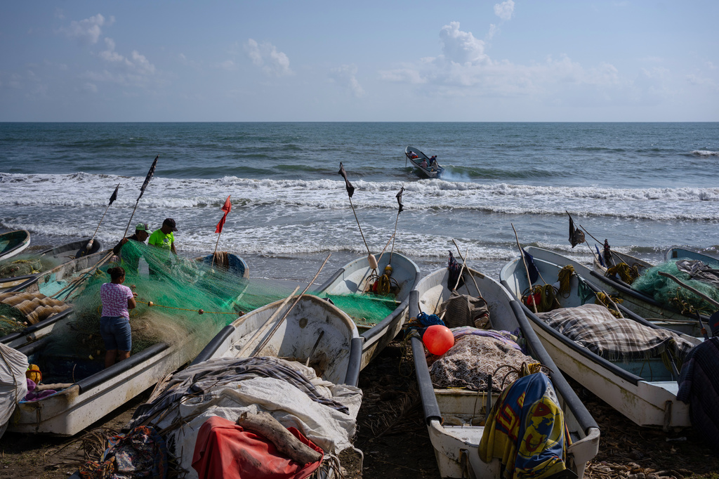 Fishermen untangle a net after suspending fishing trips because of an oil spill in the Gulf of Mexico that authorities said originated from an unidentified vessel and two natural oil seeps in Salinas, Mexico, Thursday, March 26, 2026. (AP Photo/Felix Marquez)