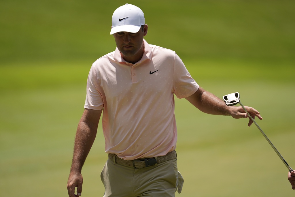 Scottie Scheffler hands his putter to his caddie on fourth green during the first round of the St. Jude Championship golf tournament Thursday, Aug. 7, 2025, in Memphis, Tenn. (AP Photo/George Walker IV)