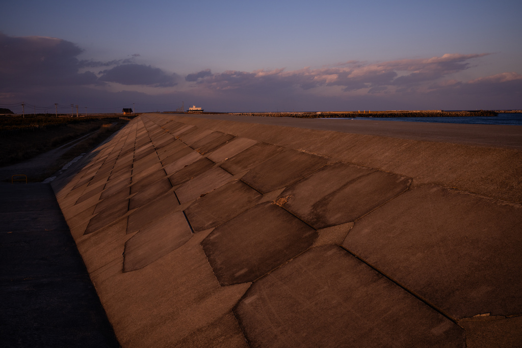 A tsunami seawall stands along the coast in Namie, Fukushima Prefecture, Thursday, Feb. 12, 2026. (AP Photo/Louise Delmotte)