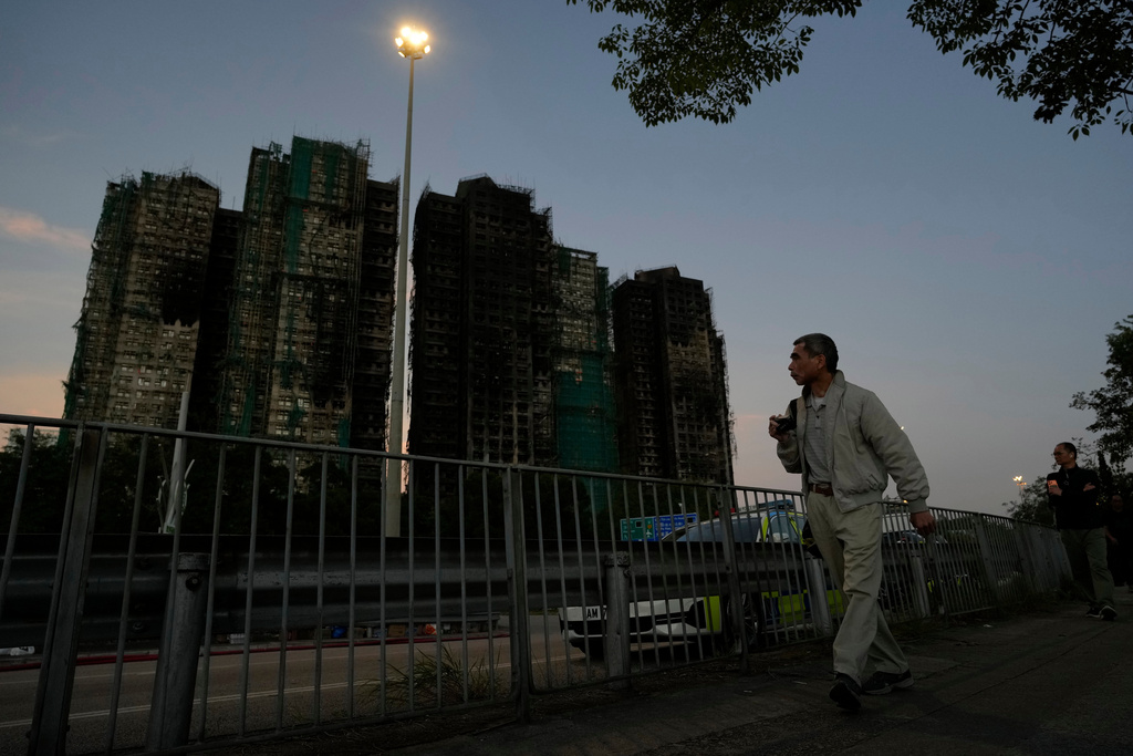 A man walks past the burnt buildings after a deadly fire that started Wednesday at Wang Fuk Court, a residential estate in the Tai Po district of Hong Kong's New Territories, Friday, Nov. 28 2025. (AP Photo/Ng Han Guan)
