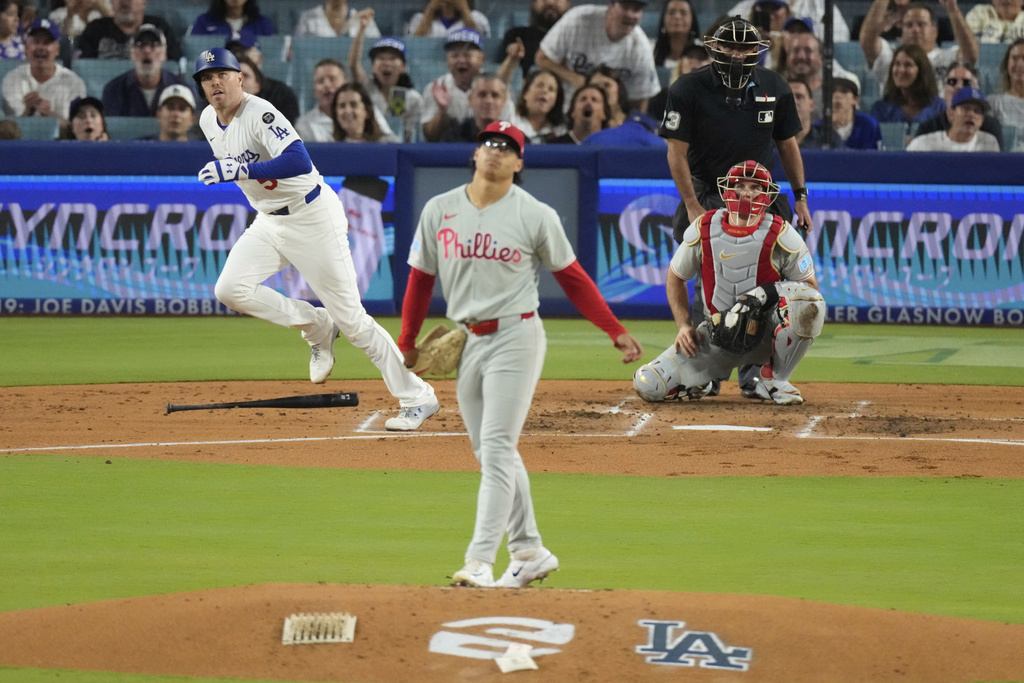 Los Angeles Dodgers' Freddie Freeman, left, watches his home run along with Philadelphia Phillies starting pitcher Jesus Luzardo, center, and catcher J.T. Realmuto during the second inning of a baseball game Wednesday, Sept. 17, 2025, in Los Angeles. (AP Photo/Mark J. Terrill)