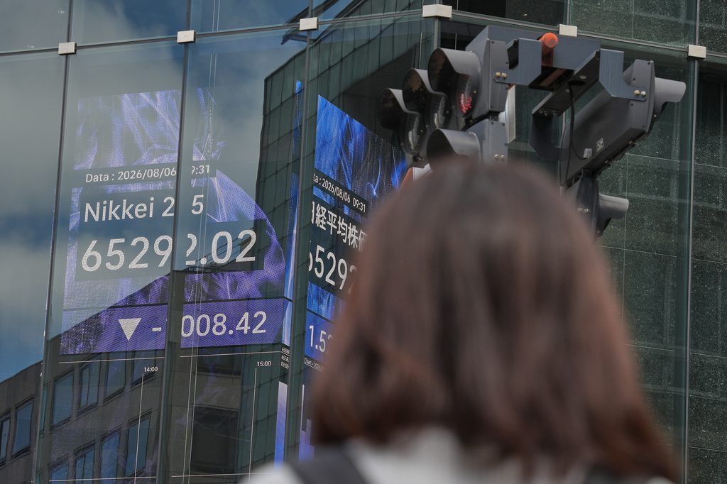 A person stands near an electronic board showing Japan's Nikkei index at a securities firm Thursday, Aug. 6, 2026, in Tokyo. (AP Photo/Eugene Hoshiko)