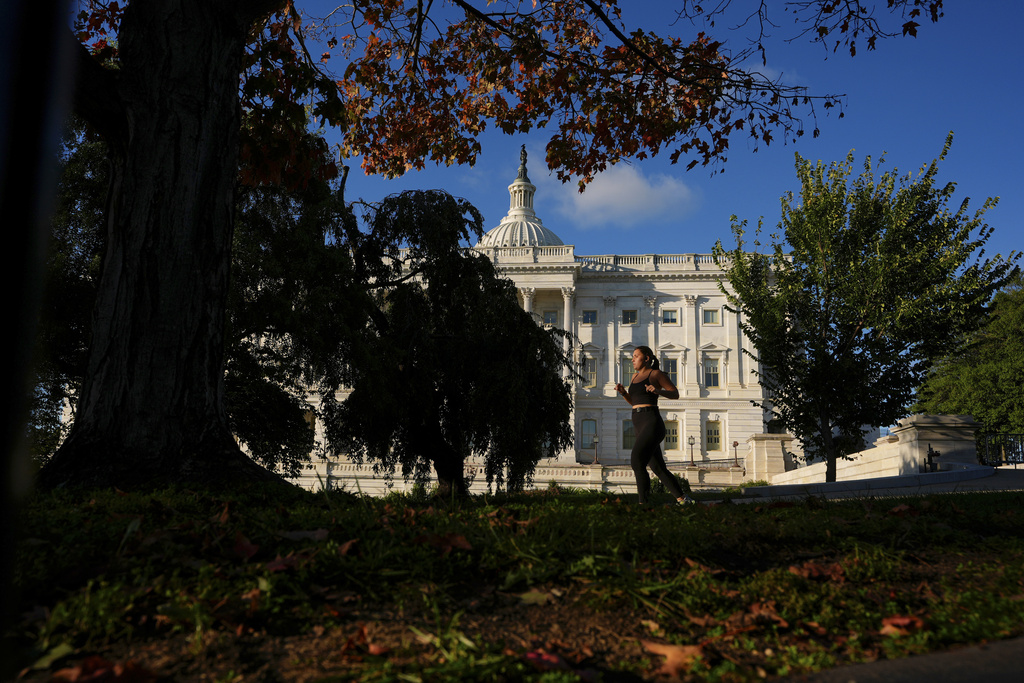 A person jogs past the U.S. Capitol amid fall foliage, Tuesday, Oct. 14, 2025, in Washington. (AP Photo/Carolyn Kaster)