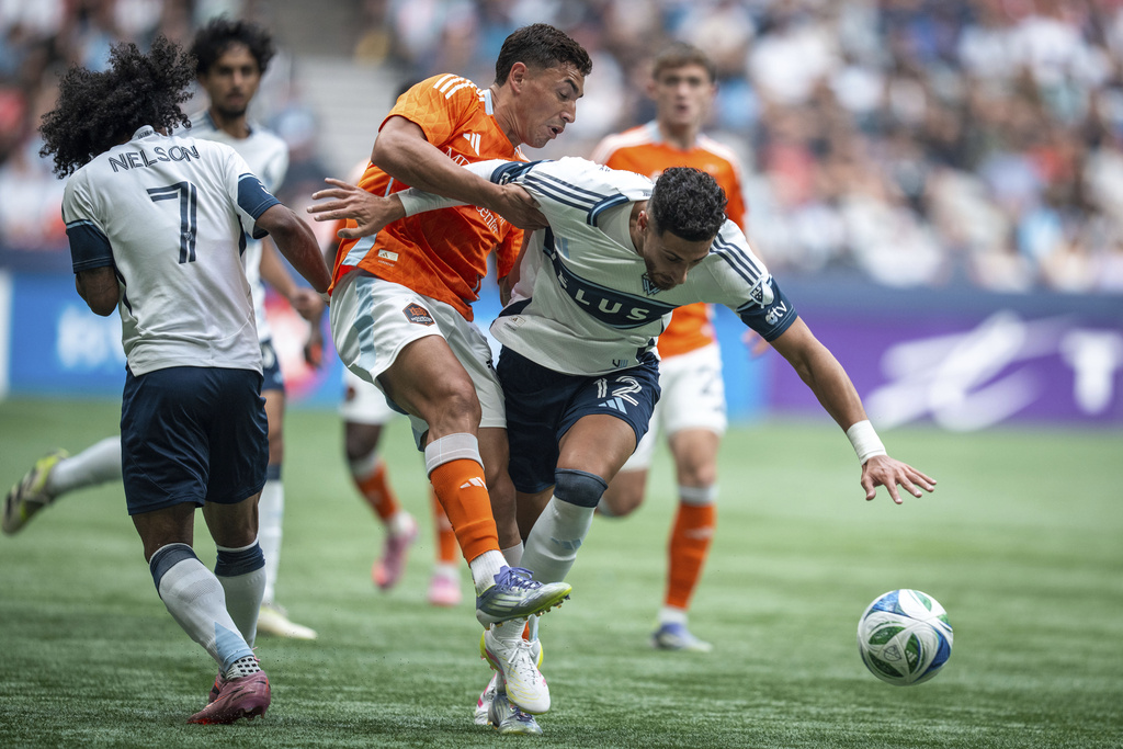 Houston Dynamo's Ezequiel Ponce (and Vancouver Whitecaps' Belal Halbouni (12) collide as they vie for the ball during the first half of an MLS soccer match in Vancouver, British Columbia, Sunday, Aug. 17, 2025. (Ethan Cairns/The Canadian Press via AP)