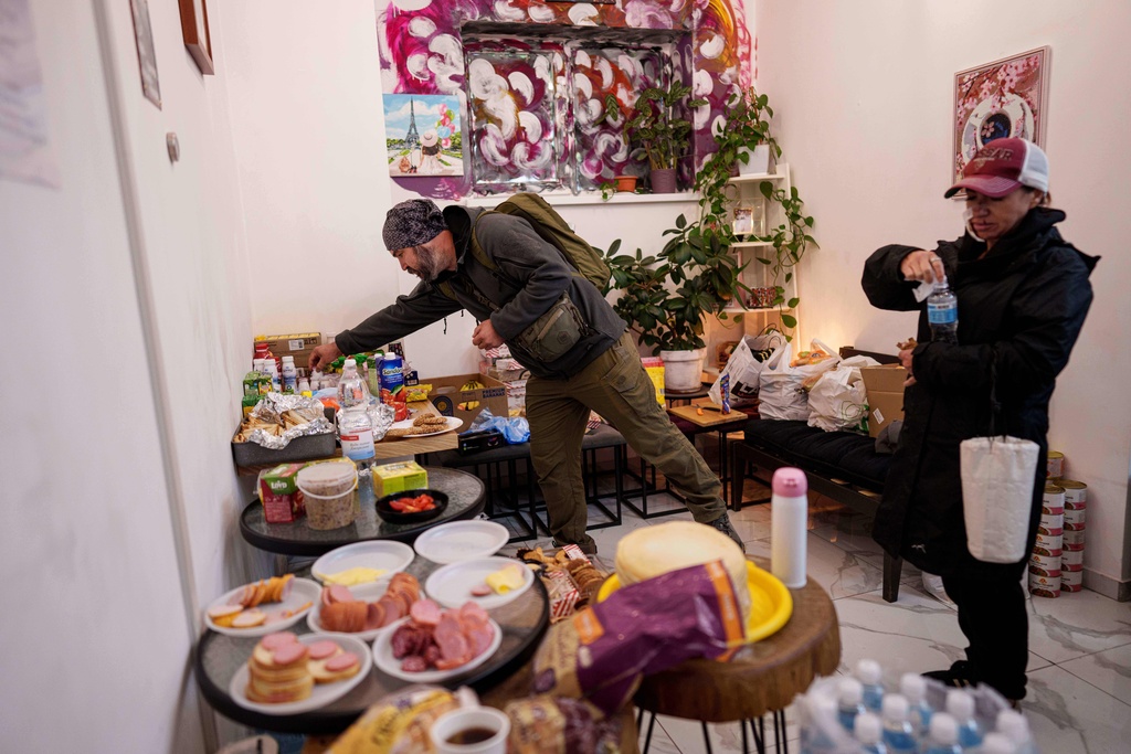 People who's apartments been damaged make sandwiches at the coffee shop "Navzaiem", in apartment building which was damaged after a Russian attack in Kyiv, Ukraine, on Monday, Sept. 29, 2025. (AP Photo/Evgeniy Maloletka)