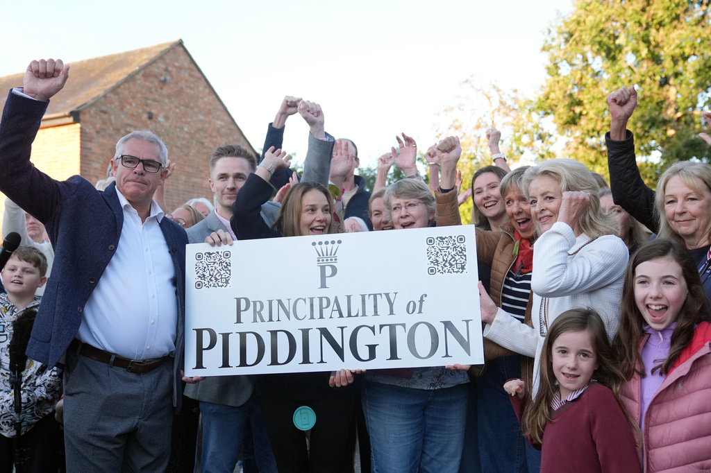 Local residents pose with a "Principality of Piddington" sign in the village of Piddington, Oxfordshire, England, Wednesday, Sept. 16, 2026, after they voted overwhelmingly to become an independent state in a symbolic "referendum". (Joe Giddens/PA via AP)