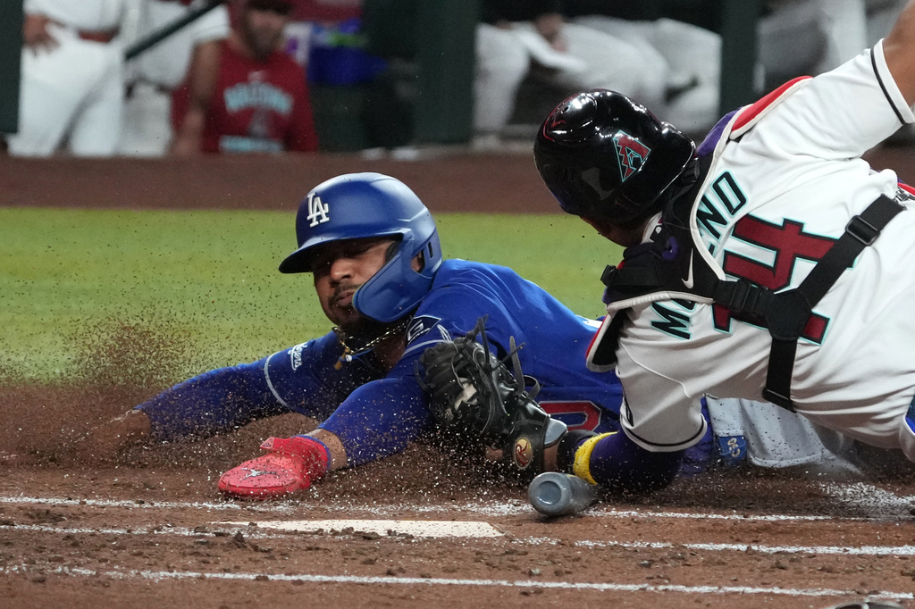 Arizona Diamondbacks catcher Gabriel Moreno (14) tags out Los Angeles Dodgers' Mookie Betts, left, who was trying to steal home on a ball hit by Max Muncy in the first inning of a baseball game, Monday, June 1, 2026, in Phoenix. (AP Photo/Rick Scuteri)