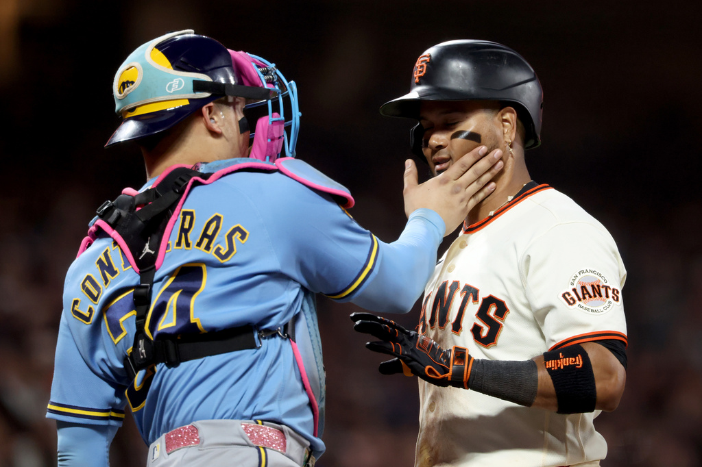 Milwaukee Brewers catcher William Contreras (24) playfully slaps San Francisco Giants' Luis Arraez, right, during the seventh inning of a baseball game in San Francisco, Monday, July 27, 2026. (AP Photo/Jed Jacobsohn)