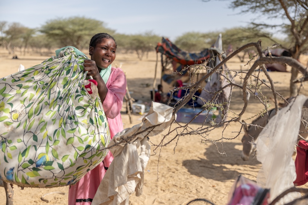 A woman from Mali carries her belongings in a makeshift refugee camp near Douankara, in the Hodh El Chargui Region, Mauritania, Nov. 6, 2025. (AP Photo/Caitlin Kelly)