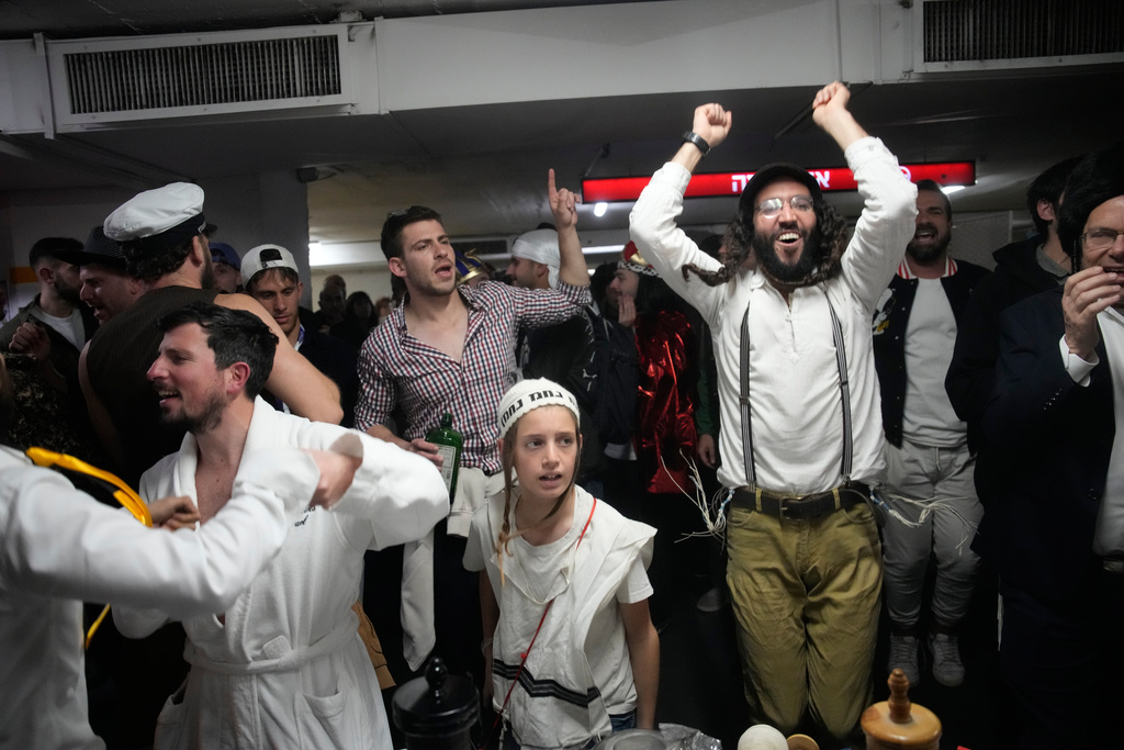 Israelis, some dressed in costumes celebrate the Jewish holiday of Purim in an underground parking garage as a precaution against possible Iranian missile attacks, in Tel Aviv, Israel, Monday, March 2, 2026. (AP Photo/Ohad Zwigenberg)
