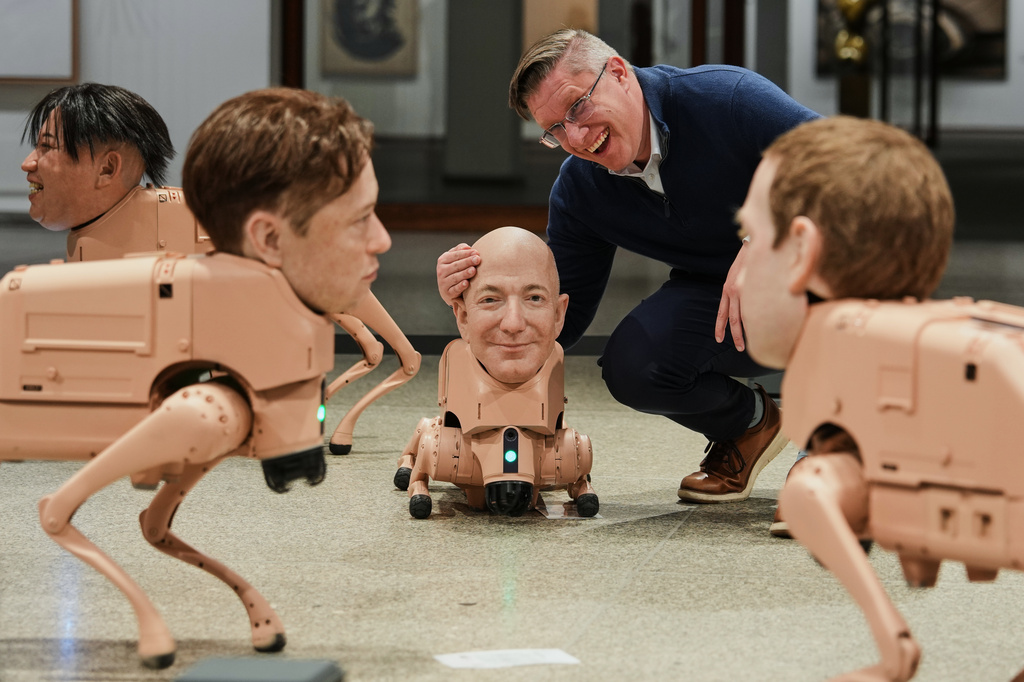 Artist Beeple, Mike Winkelmann, poses inside his installation titled Regular Animals, with robots in the likeness of Kim Jong Un, left, Elon Musk, second left, Kim Jong Un, Jeff Bezos, center, and Mark Zuckerberg, right, at the Neue Nationalgalerie museum in Berlin, Germany, Tuesday, April 28, 2026. (AP Photo/Markus Schreiber)