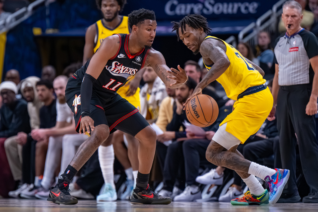 Philadelphia 76ers forward Justin Edwards (11) swipes at the ball being controlled by Indiana Pacers guard Quenton Jackson, right, during the first half of an NBA basketball game in Indianapolis, Friday, April 10, 2026. (AP Photo/Doug McSchooler)