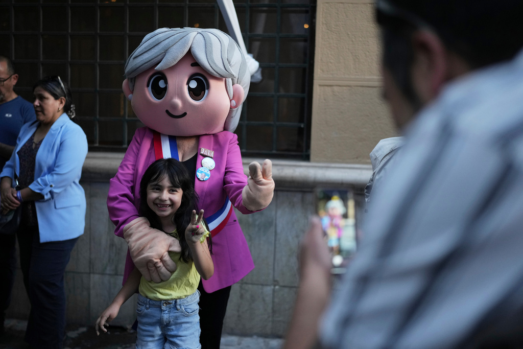 A child poses with a person dressed up as presidential candidate Jeannette Jara of the Unidad por Chile coalition after the polls closed during general elections in Santiago, Chile, Sunday, Nov. 16, 2025. (AP Photo/Natacha Pisarenko)
