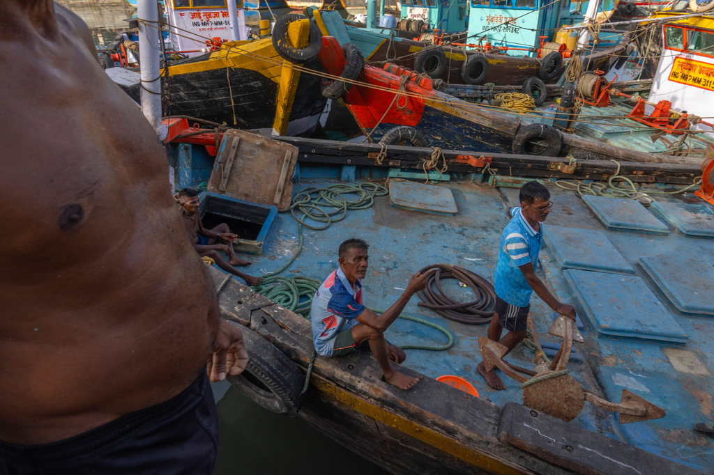 Fishermen rest on a fishing boat anchored idle due the price high at Sassoon Dock in Mumbai, India, Tuesday, April 7, 2026. (AP Photo/Rafiq Maqbool)