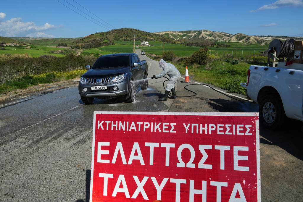 An employee sprays a car inside a blocked section of a livestock zone containing thousands of goats, sheep, and cows following an outbreak of foot-and-mouth disease in the Troulloi area near Larnaca, Cyprus, Wednesday, Feb. 25, 2026. (AP Photo/Petros Karadjias)
