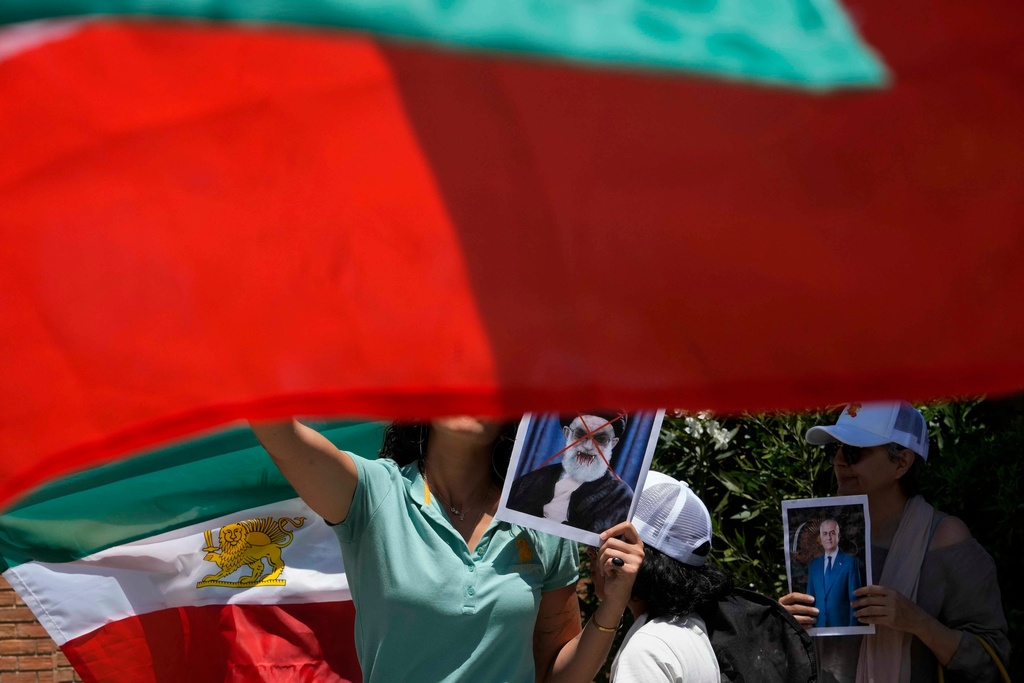 FILE - A protester holds a defaced poster of Iran's Supreme Leader Ayatollah Ali Khamenei, center, during a rally in support of anti-government protests in Iran, outside Iran's embassy in Santiago, Chile, Jan. 13, 2026. (AP Photo/Esteban Felix, File)
