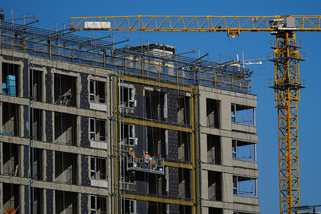 Workers labor on a scaffolding to install insulation layers on a residential building under construction in Beijing on Dec. 3, 2025. (AP Photo/Andy Wong)