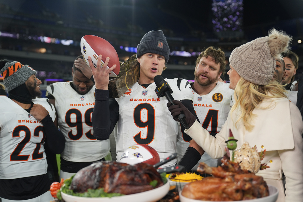 Cincinnati Bengals quarterback Joe Burrow (9) joined by safety Geno Stone (22), defensive end Myles Murphy (99) and center Ted Karras (64) talks with NBC Sports sideline reporter Melissa Stark, right, after NFL football game against the Baltimore Ravens, Thursday, Nov. 27, 2025, in Baltimore. (AP Photo/Stephanie Scarbrough)