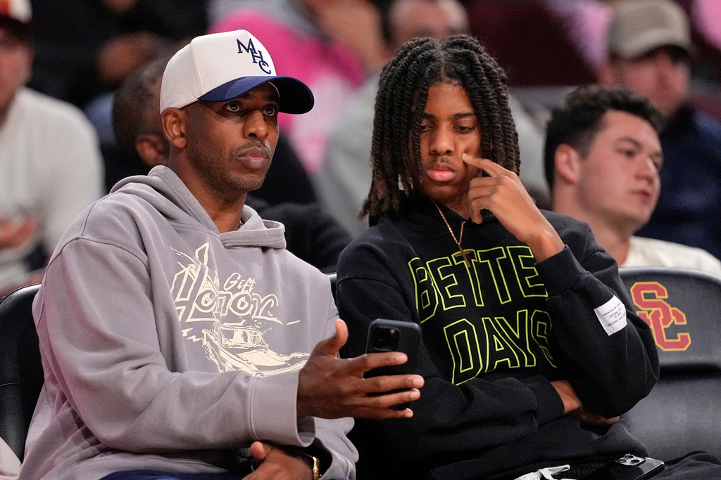 Basketball player Chris Paul, left, sits with his son Chris Paul Jr. during the second half of an NCAA college basketball game between Southern California and Northwestern, Wednesday, Jan. 21, 2026, in Los Angeles. (AP Photo/Mark J. Terrill)