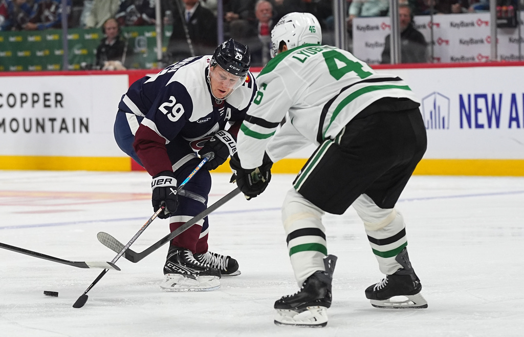 Dallas Stars defenseman Ilya Lyubushkin, front, knocks the puck away from Colorado Avalanche center Nathan MacKinnon in the first period of an NHL hockey game Saturday, Oct. 11, 2025, in Denver. (AP Photo/David Zalubowski)