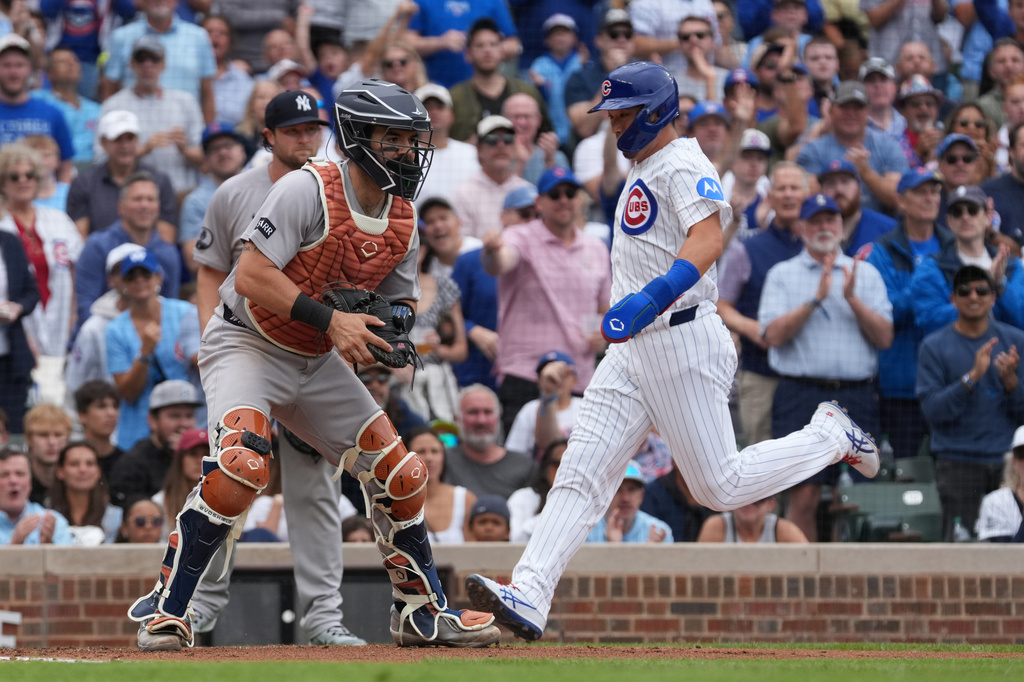 Chicago Cubs' Seiya Suzuki, right, scores as New York Yankees catcher Austin Wells, left, waits for a throw during the fourth inning of a baseball game Sunday, Aug. 2, 2026, in Chicago. (AP Photo/David Banks)