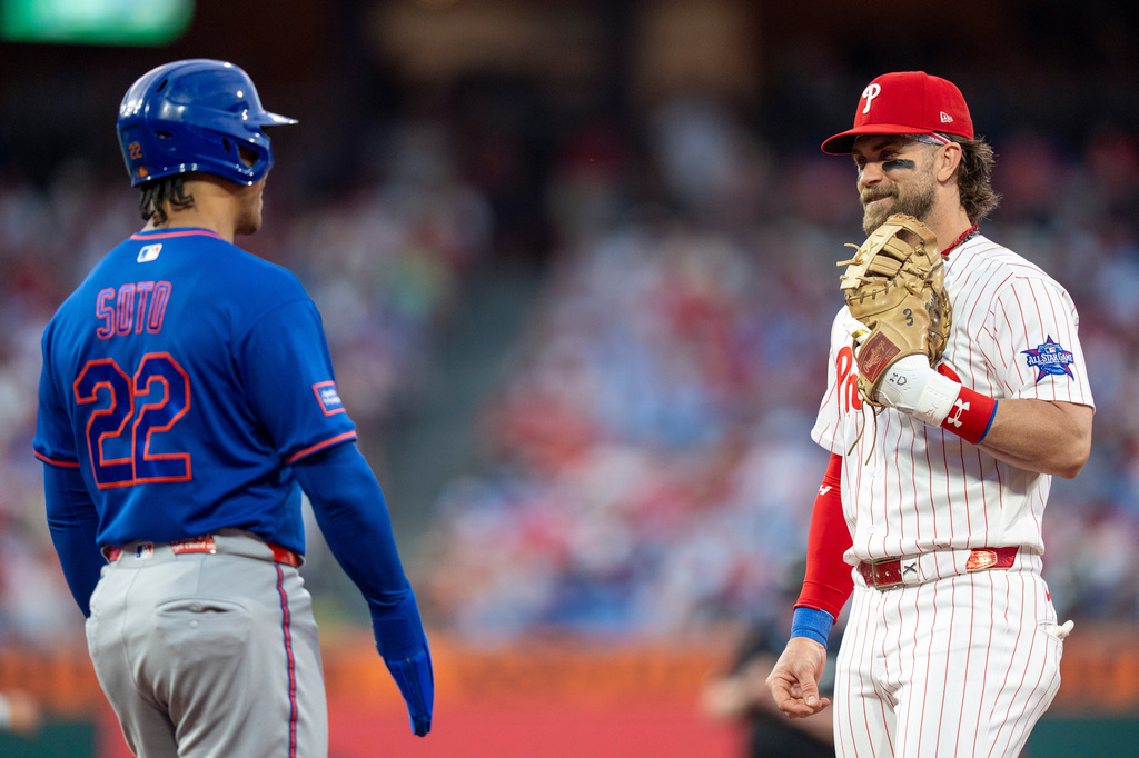 Philadelphia Phillies first baseman Bryce Harper, right, talks with New York Mets' Juan Soto, left, during the third inning of a baseball game, Saturday, June 20, 2026, in Philadelphia. (AP Photo/Chris Szagola)