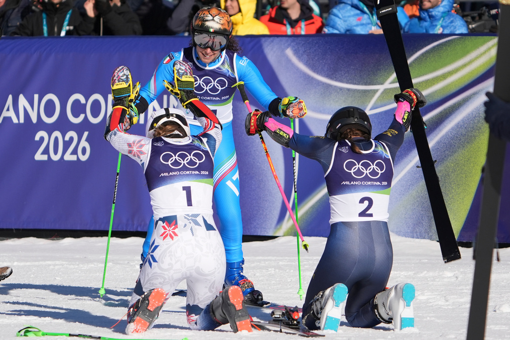 Sweden's Sara Hector, right, and Norway's Thea Louise Stjernesund bow to Italy's Federica Brignone, center, at the finish area of an alpine ski, women's giant slalom race, at the 2026 Winter Olympics, in Cortina d'Ampezzo, Italy, Sunday, Feb. 15, 2026. (AP Photo/Jacquelyn Martin)