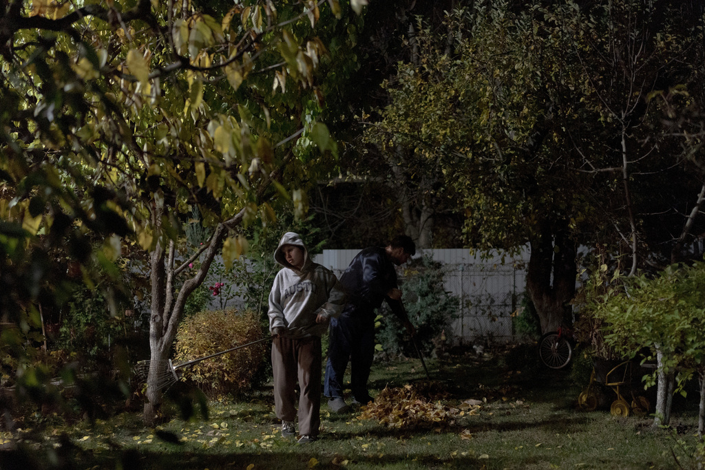 CORRECTS FAMILY NAME TO ADAMCHUK - Oleksandr Adamchuk, right, rakes leaves in the yard with his oldest daughter Anna, 11, after work, the only time Adamchuk has to spend with his family and complete chores, Friday, Oct. 24, 2025, in Kyiv region, Ukraine. (AP Photo/Julia Demaree Nikhinson)