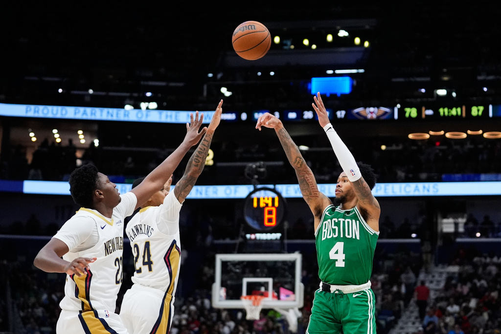 Boston Celtics guard Anfernee Simons (4) shoots against New Orleans Pelicans guard Jordan Hawkins (24) and center Derik Queen (22) in the second half of an NBA basketball game, Monday, Oct. 27, 2025, in New Orleans. (AP Photo/Gerald Herbert)