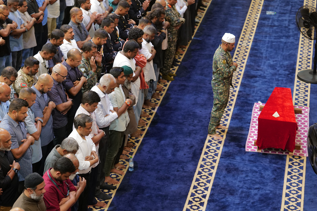 Maldivian President Mohamed Muizzu along with National Defense Force members prays in front of the remains of military diver Mohamed Mahudhee who died during search and rescue operation of four Italian divers, during his funeral in Male, Maldives, Saturday, May 16, 2026. (AP Photo/Mohamed Sharhaan)