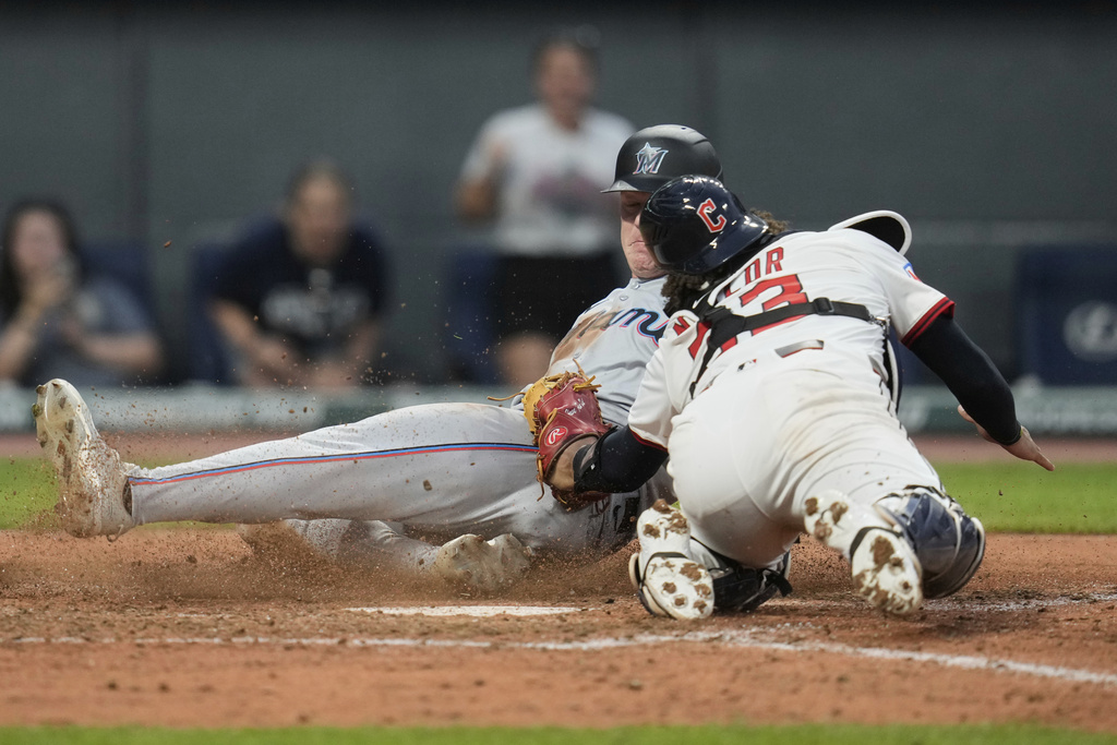 Cleveland Guardians catcher Bo Naylor, right, tags out Miami Marlins first baseman Eric Wagaman, left, at home plate in the sixth inning of a baseball game in Cleveland, Tuesday, Aug. 12, 2025. (AP Photo/Sue Ogrocki)