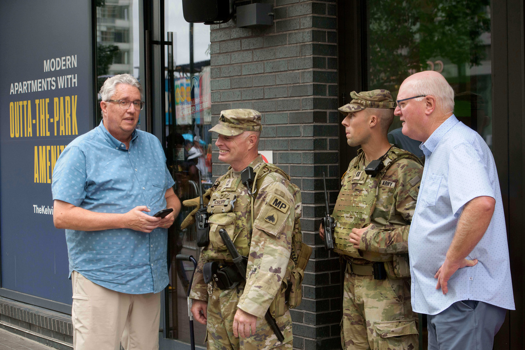 FILE - Steve DeBoer, left, and Harris Kruse, right, talk with members of the District of Columbia National Guard patrolling the area near Nationals Park on game day in Washington, Aug. 19, 2025. (AP Photo/Rod Lamkey, Jr., File)
