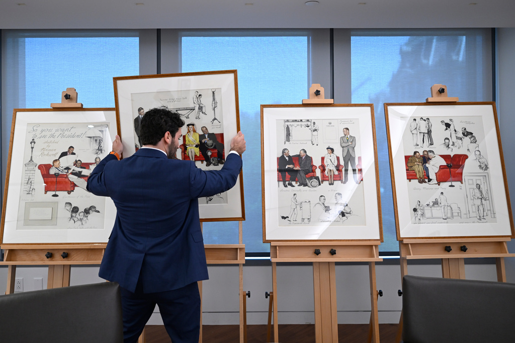 Luke Boorady, of the White House Historical Association, arranges a suite of four interrelated paintings by Norman Rockwell titled, "So You Want to See the President!" at the association's offices Wednesday, June 10, 2026, in Washington. (AP Photo/John McDonnell)