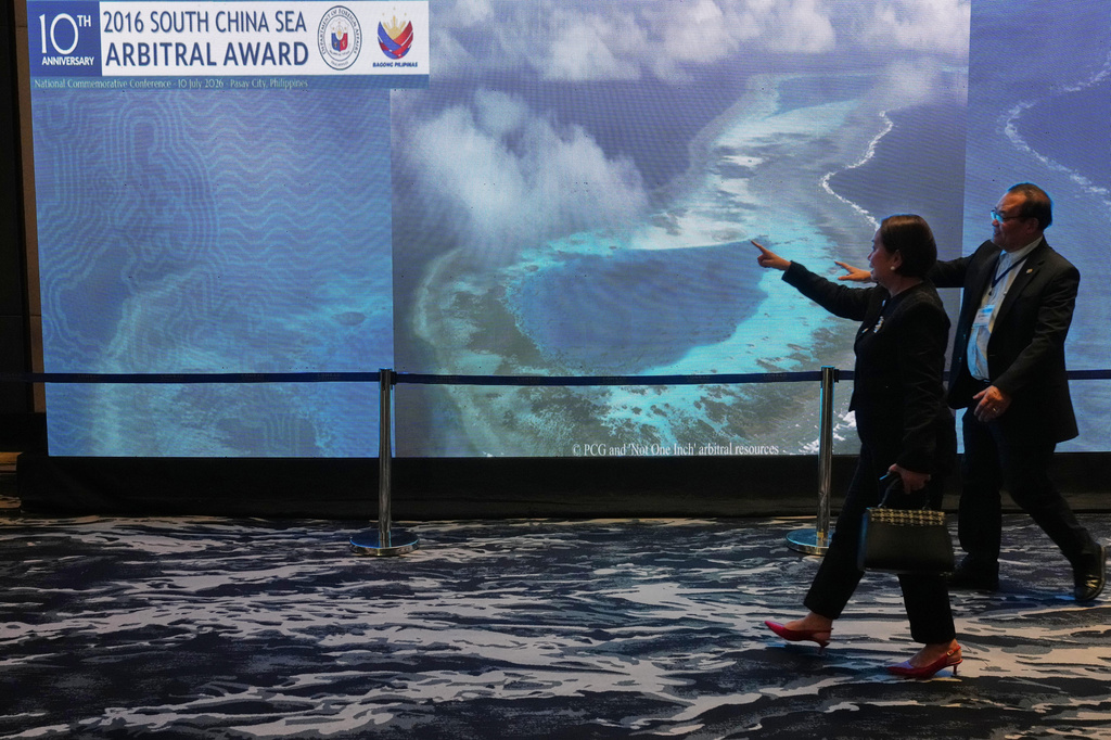 People pass by an electronic board showing areas of the disputed South China Sea during a conference to mark the 10th anniversary of a 2016 arbitration ruling which invalidated China's expansive claims during a conference in Manila, Philippines on Friday, July 10, 2026. (AP Photo/Aaron Favila)